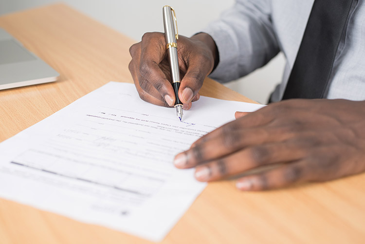 Close up of man signing a paper with a fountain pen