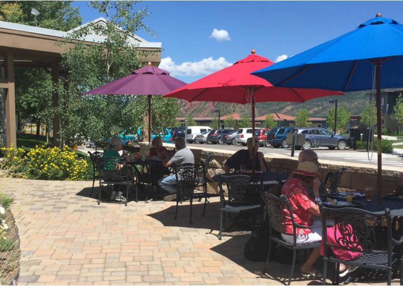Photo of dining tables outside under colorful umbrellas
